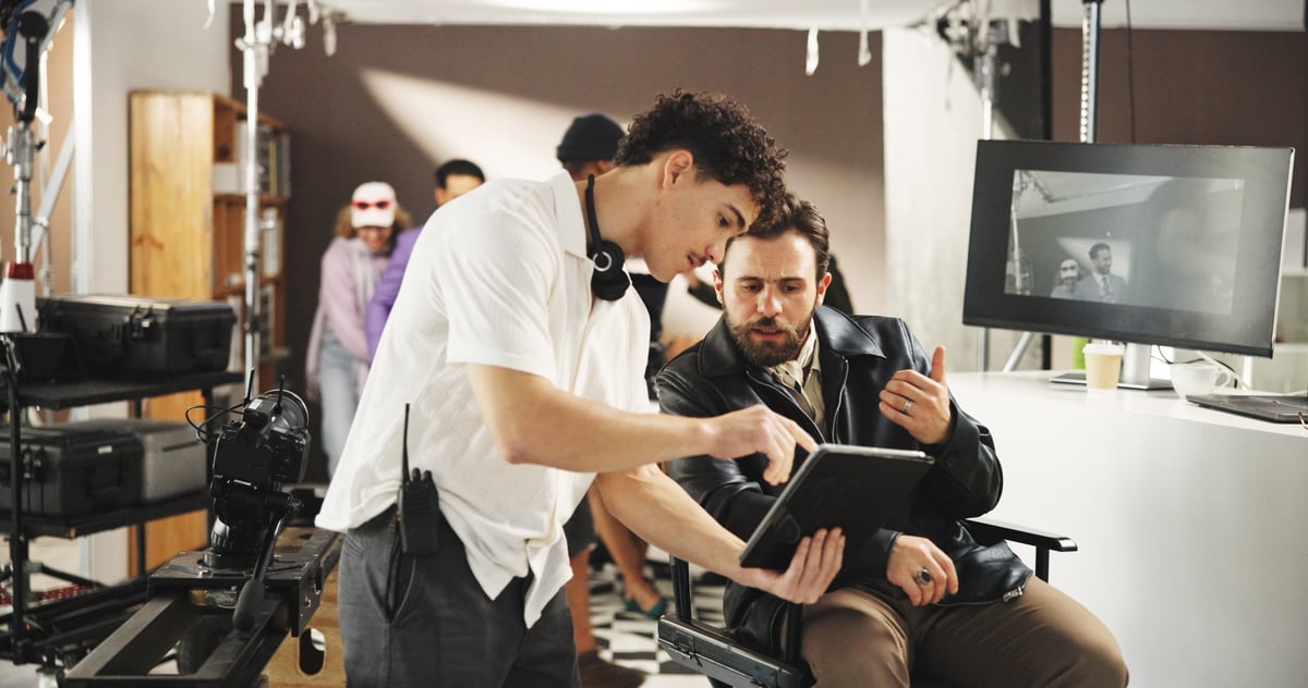 Director and producer reviewing footage on a tablet with a camera assistant inside a production studio