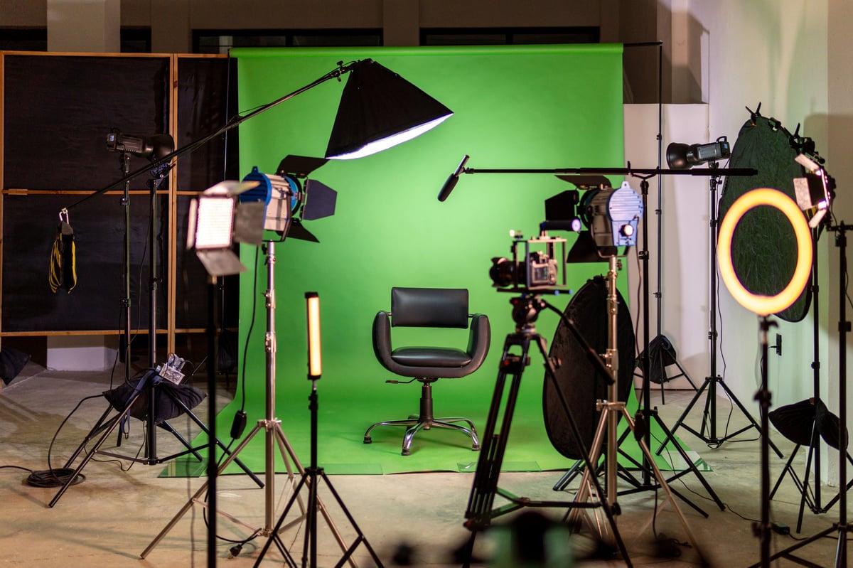 Professional green screen studio set up with camera, lights, and chair prepared for video production